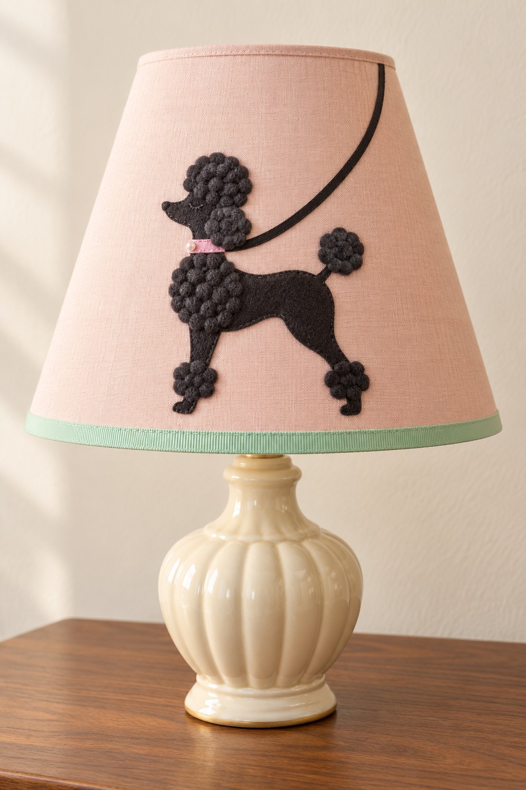 Pink lampshade with a black poodle applique, curved leash and mint lower trim