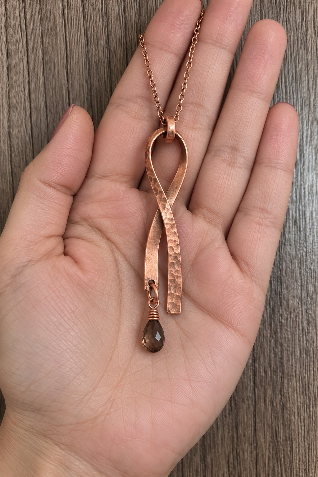 Long hammered copper ribbon pendant folded into a loop with a smoky bead below