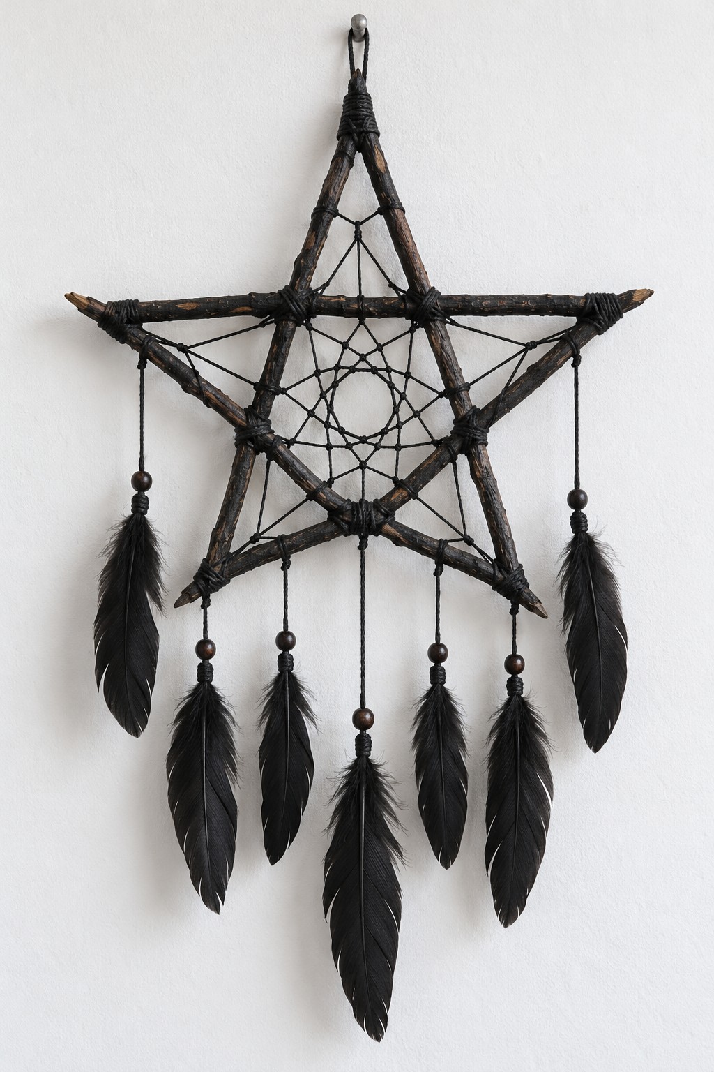 Black twig star containing a fine cord web with a row of black feather pendants underneath