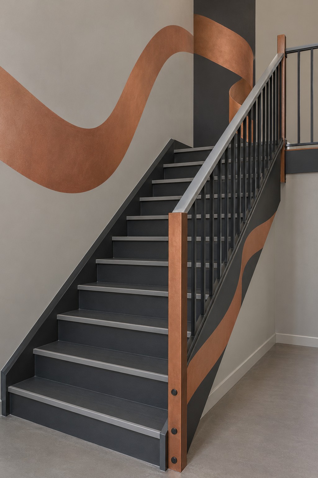 Charcoal staircase with dark metal balusters, a timber post, and a broad copper colored wall ribbon