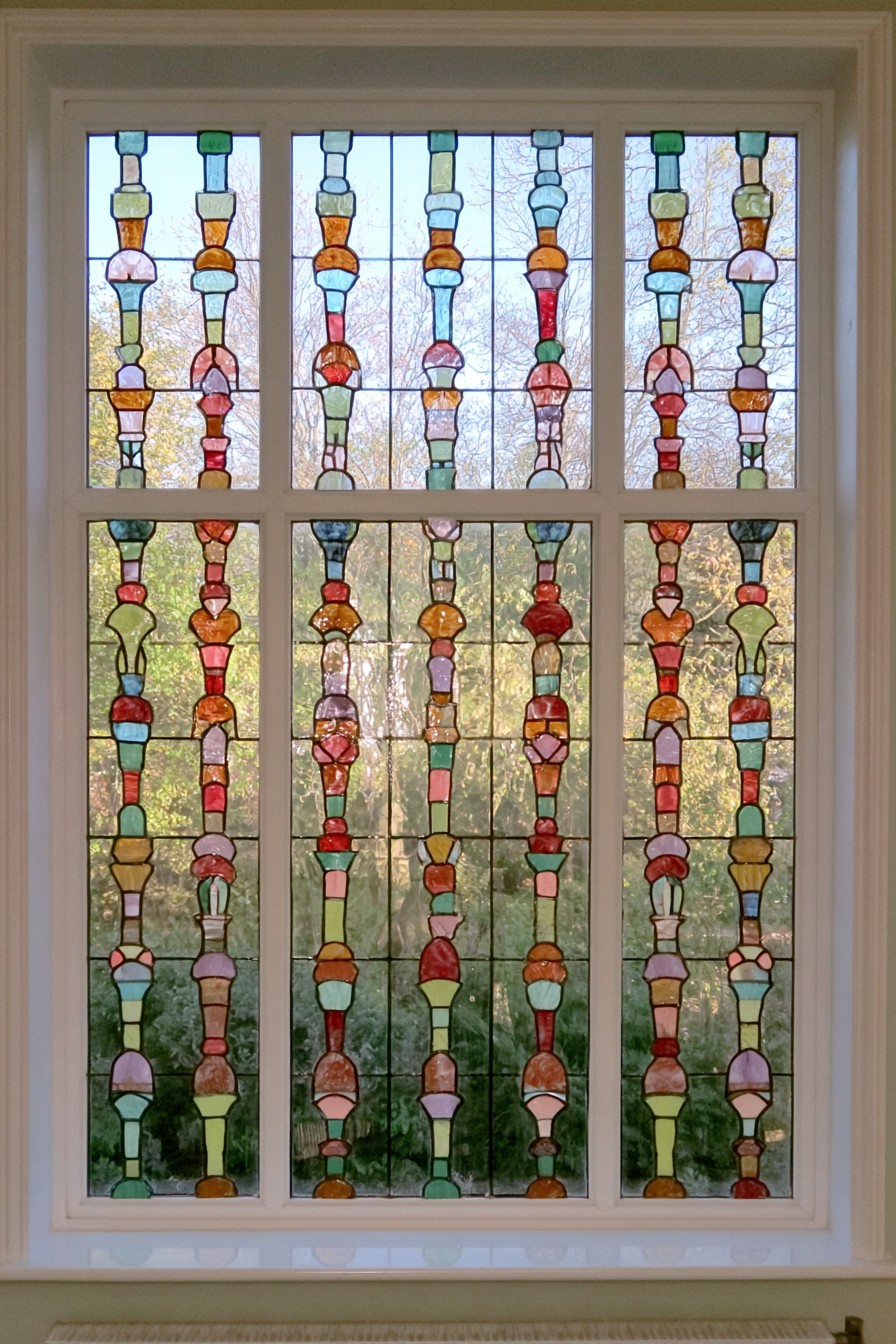 Repeated vertical strands of small multicolored geometric shapes against a mostly clear window
