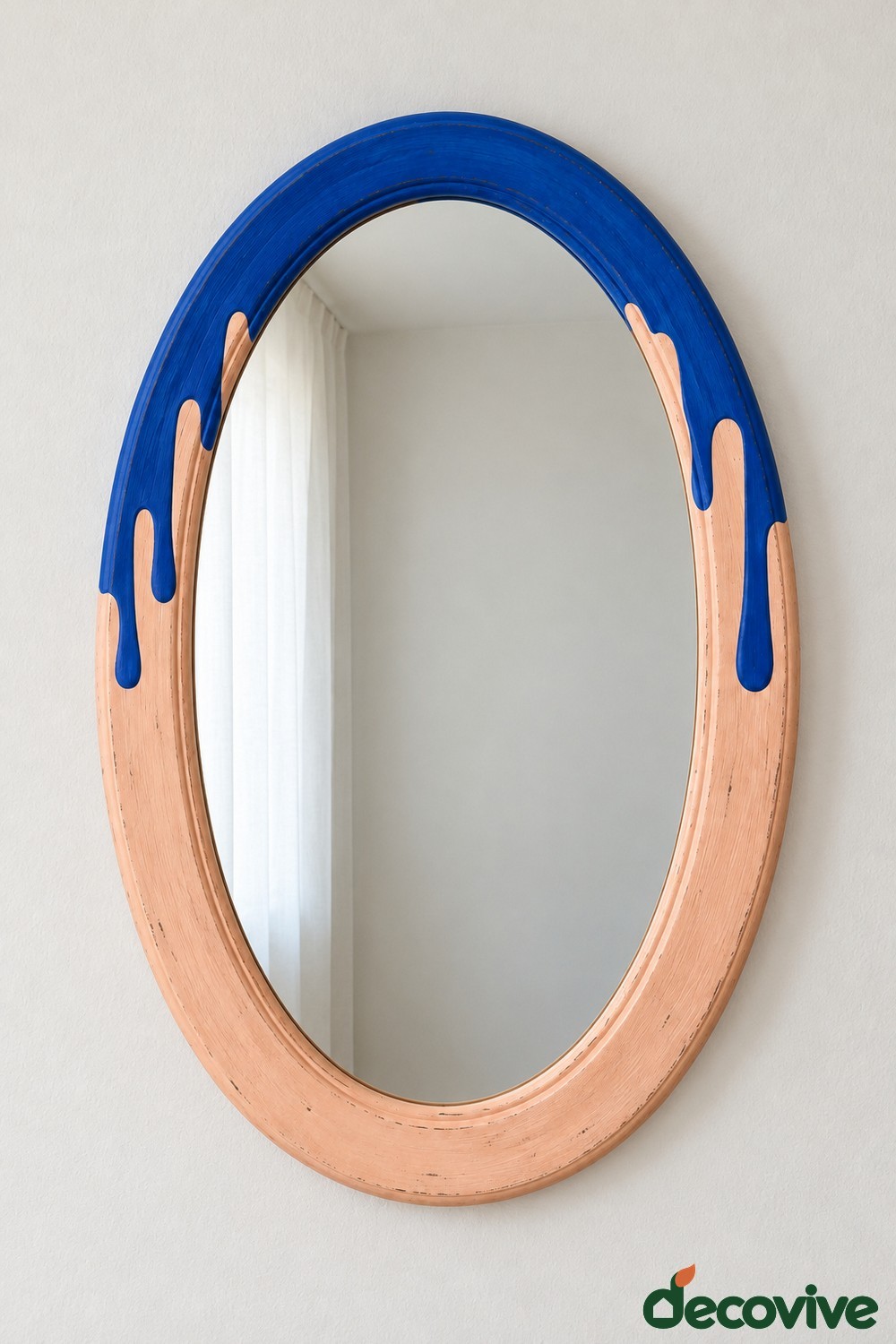 Oval peach mirror frame with cobalt blue painted drips descending from the top