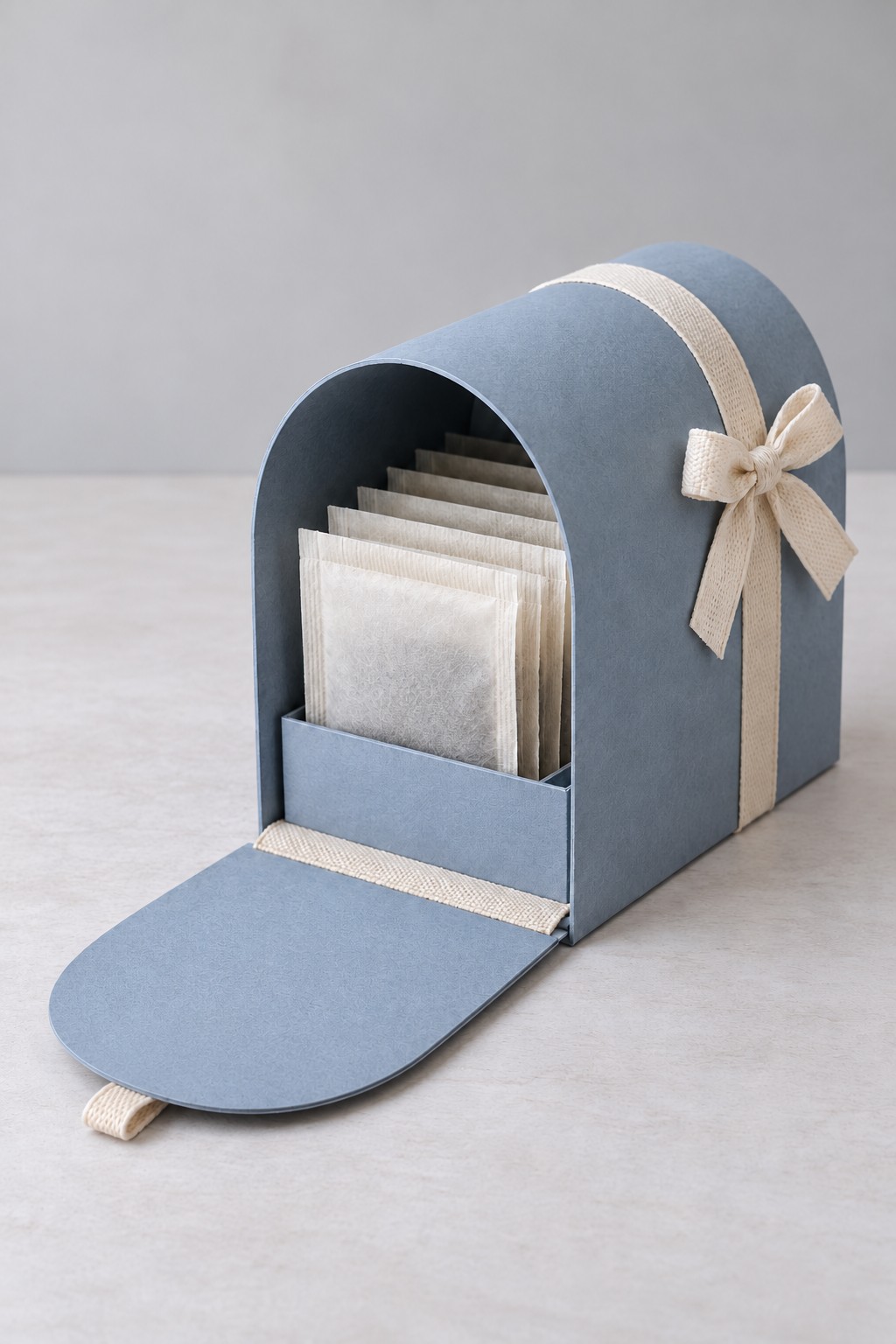 Blue arched mailbox gift box with a lowered front door and a row of tea envelopes inside