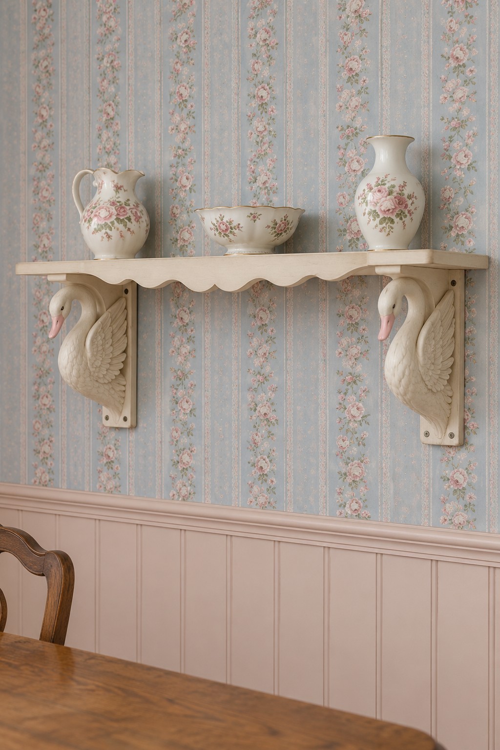 Cream scalloped wall shelf with swan shaped brackets and floral pottery against blue striped rose wallpaper