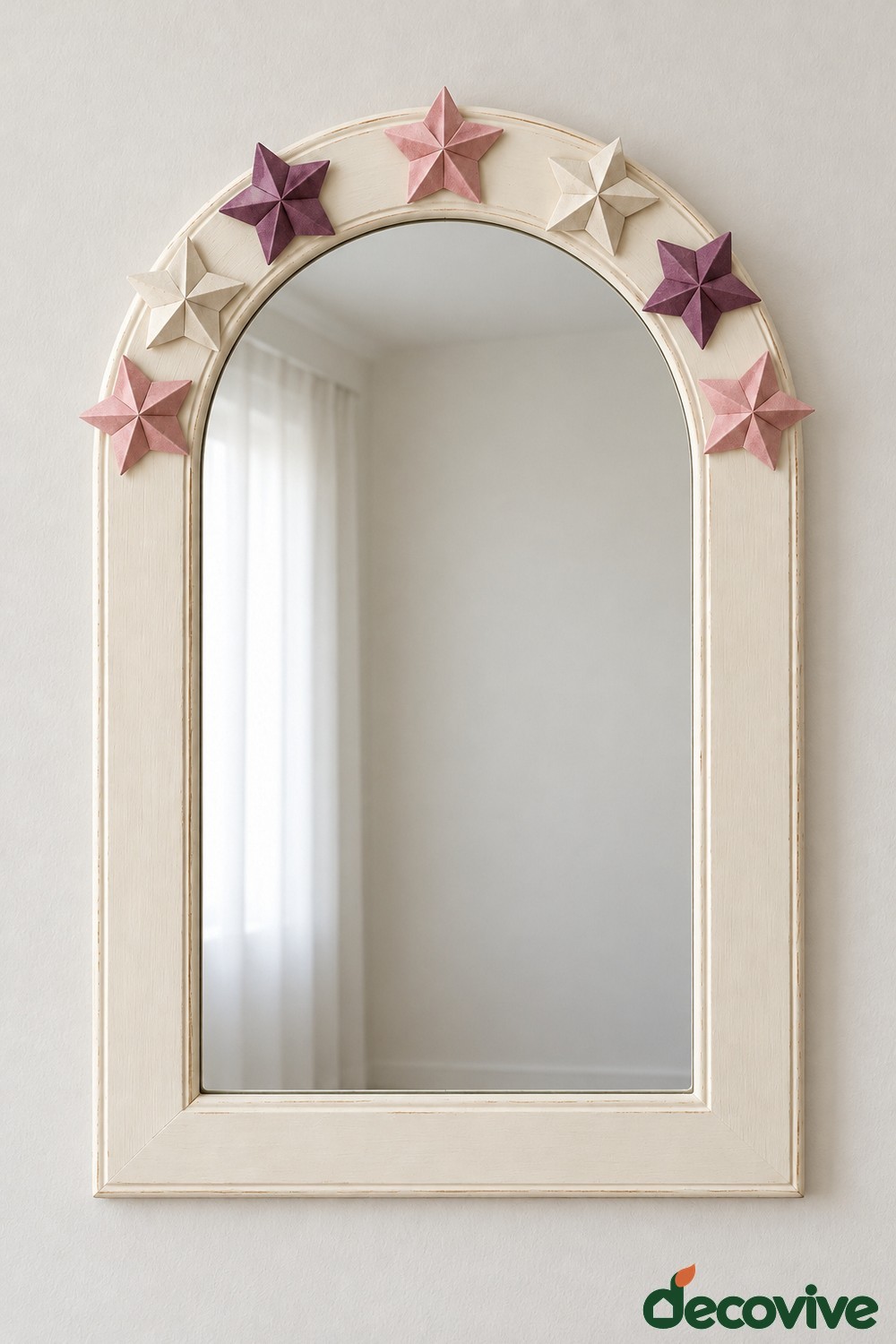Cream arched mirror with raised folded paper stars in blush ivory and plum around the upper curve