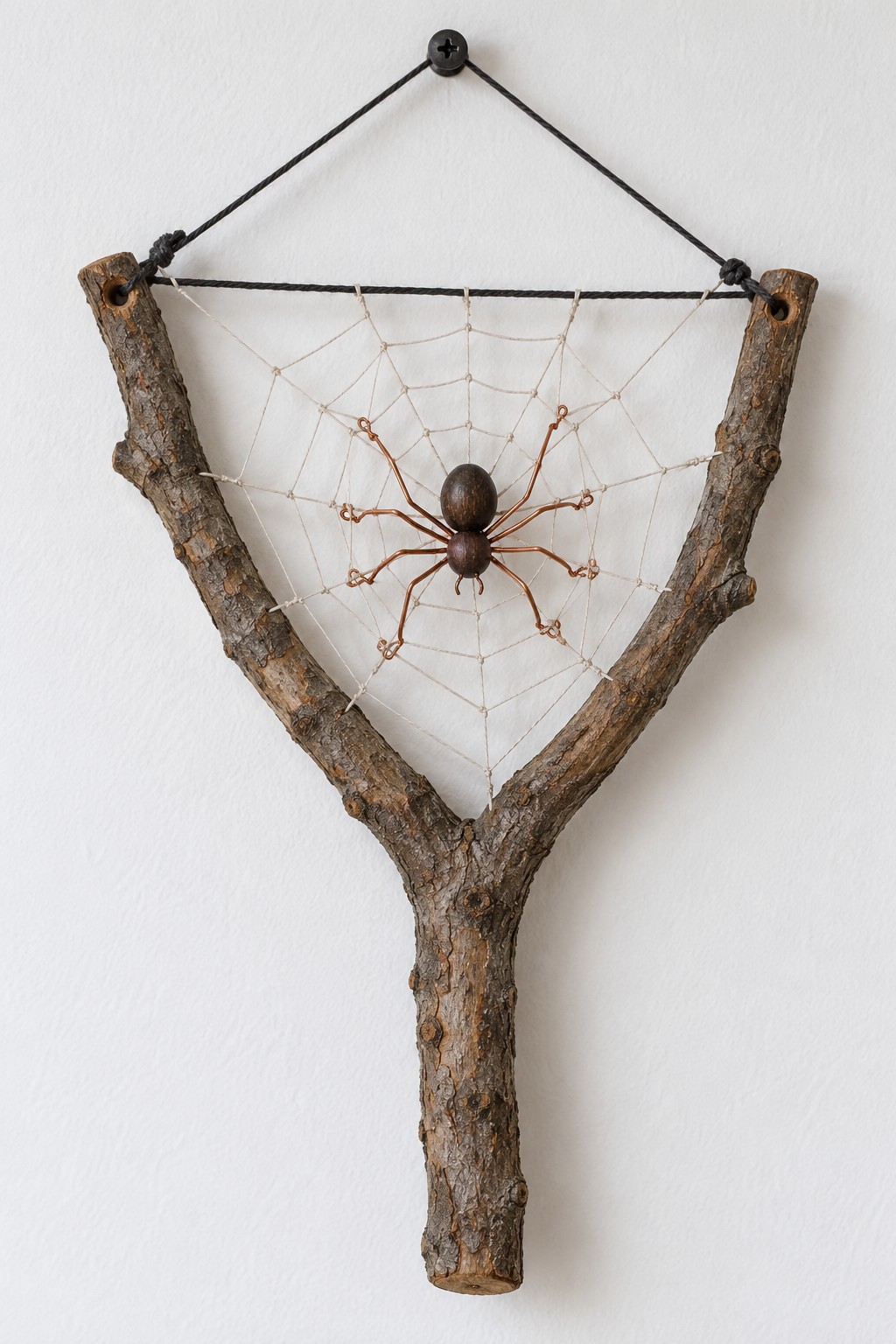Y shaped branch supporting a triangular web with a small brown spider at its center