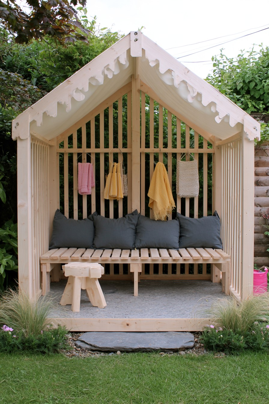 Pale slatted timber shelter with a gabled fabric covering and charcoal back cushions