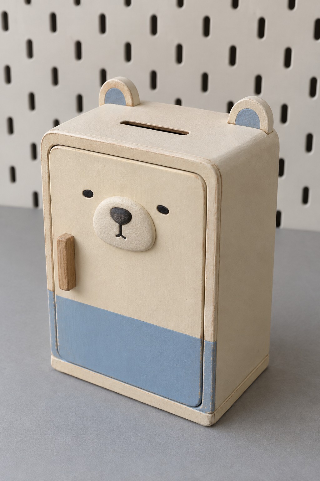 Cream and blue refrigerator shaped bear coin bank with a top slot, front door and wooden handle
