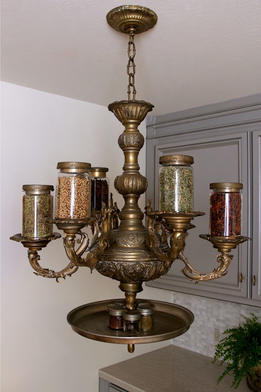 Antique brass chandelier holding glass spice jars on its arms with a tray of small jars underneath
