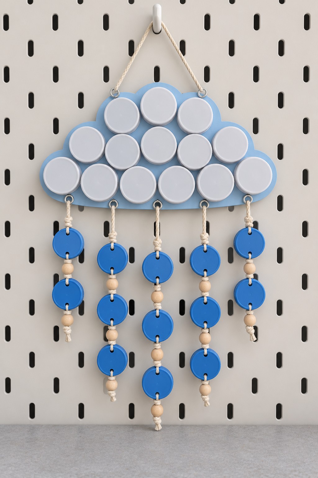 Blue cloud wall decoration covered in white plastic caps with blue cap raindrops and wooden beads on cream cord