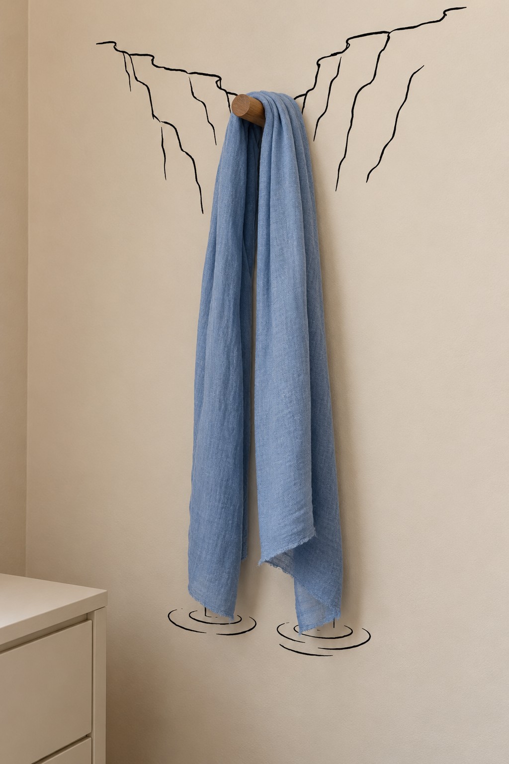Blue towel hanging from a wooden peg between drawn rock edges with painted ripples below