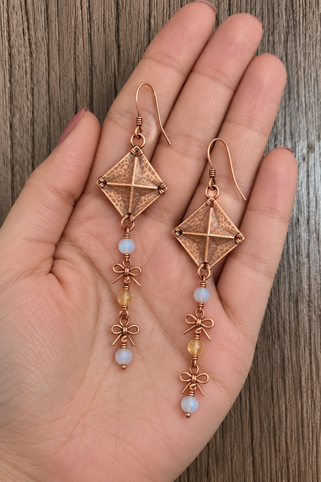 Diamond shaped copper kite earrings with crossed wire details and long beaded bow tails