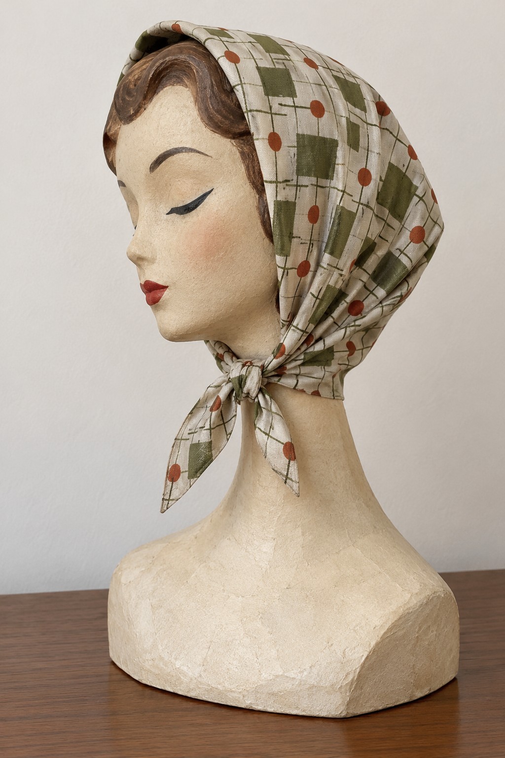 Cream headscarf with small geometric motifs tied beneath the chin of a display bust