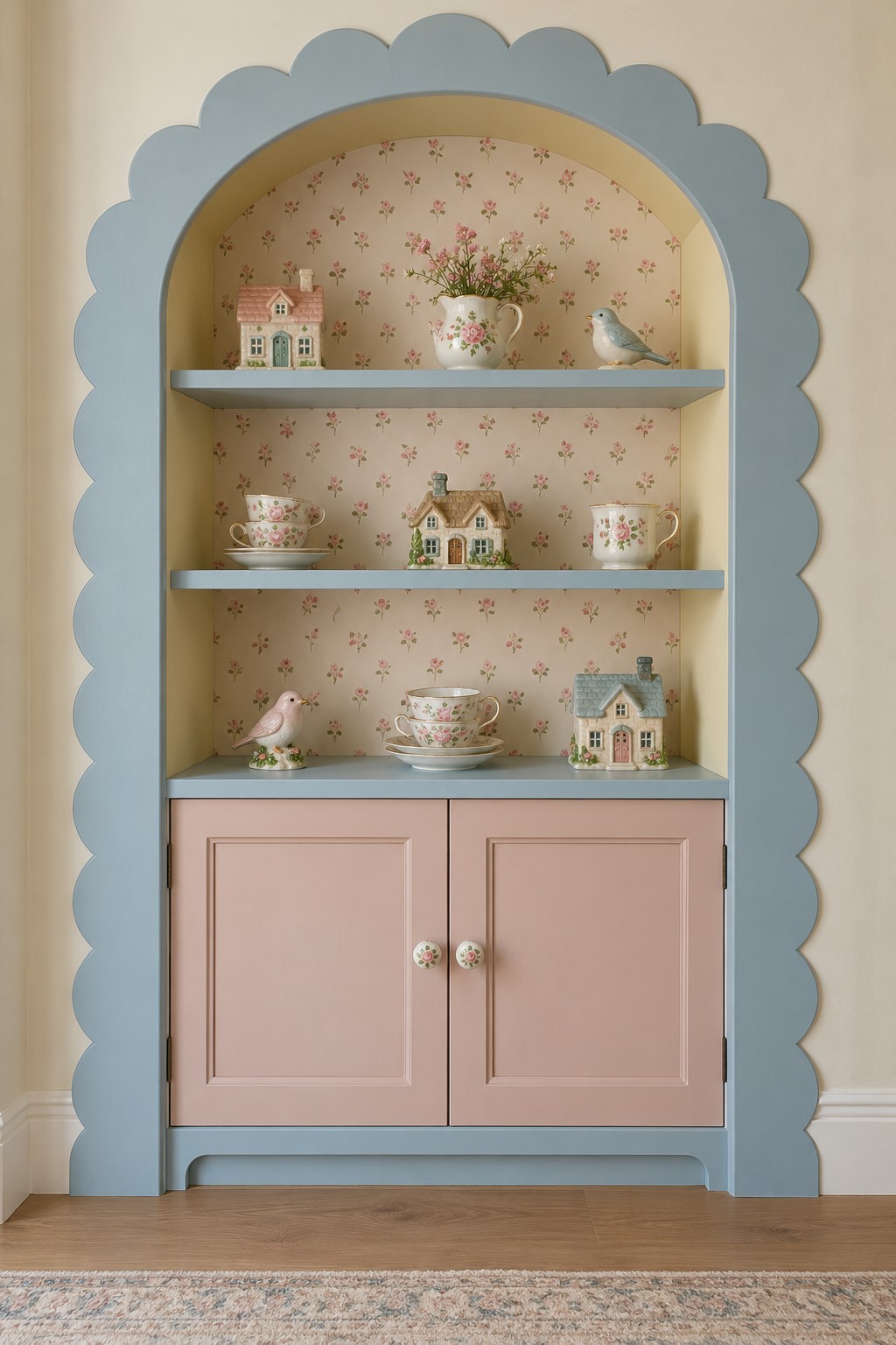 Powder blue scalloped alcove with floral backing, china displays, and blush pink cabinet doors