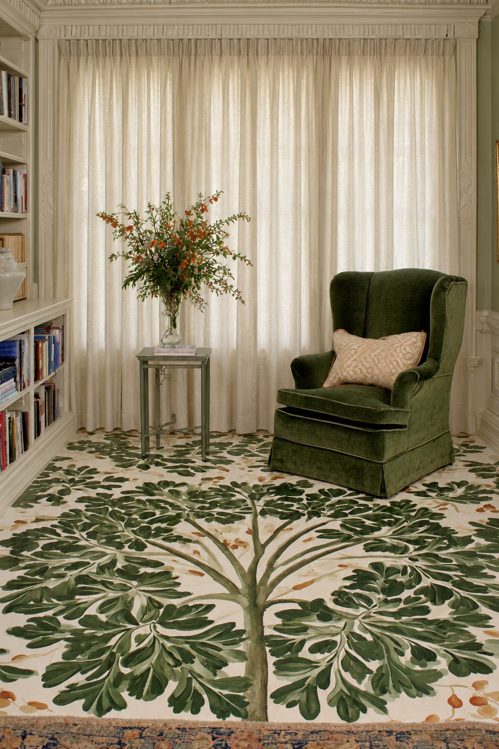 Large olive green tree silhouette spreading across a cream floor beside a green reading chair