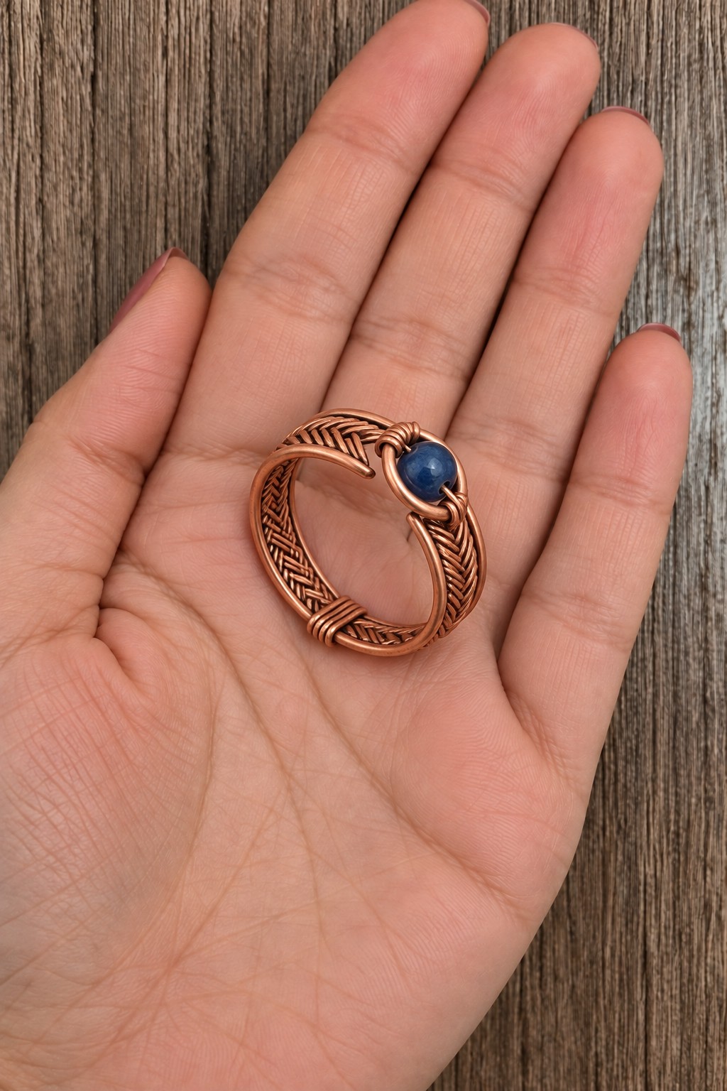Copper ring with closely woven wire shoulders and a deep blue round bead