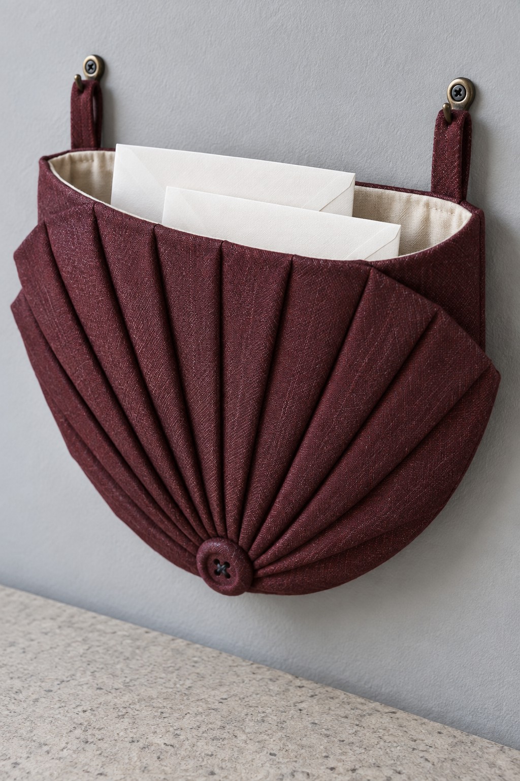 Burgundy fan shaped wall pocket holding envelopes on two hanging straps
