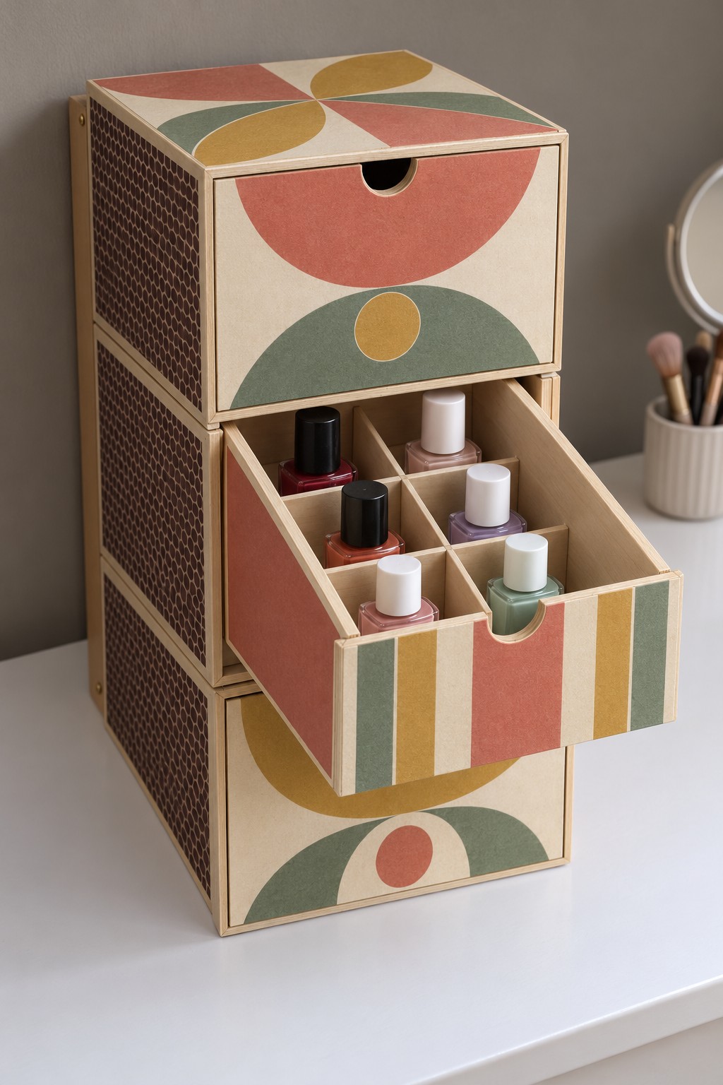 Tall patterned drawer organizer with coral, mustard, and green shapes and an open divided nail polish drawer