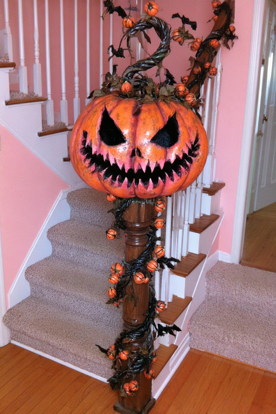 Oversized orange pumpkin and twisting dark vines decorating a stair newel