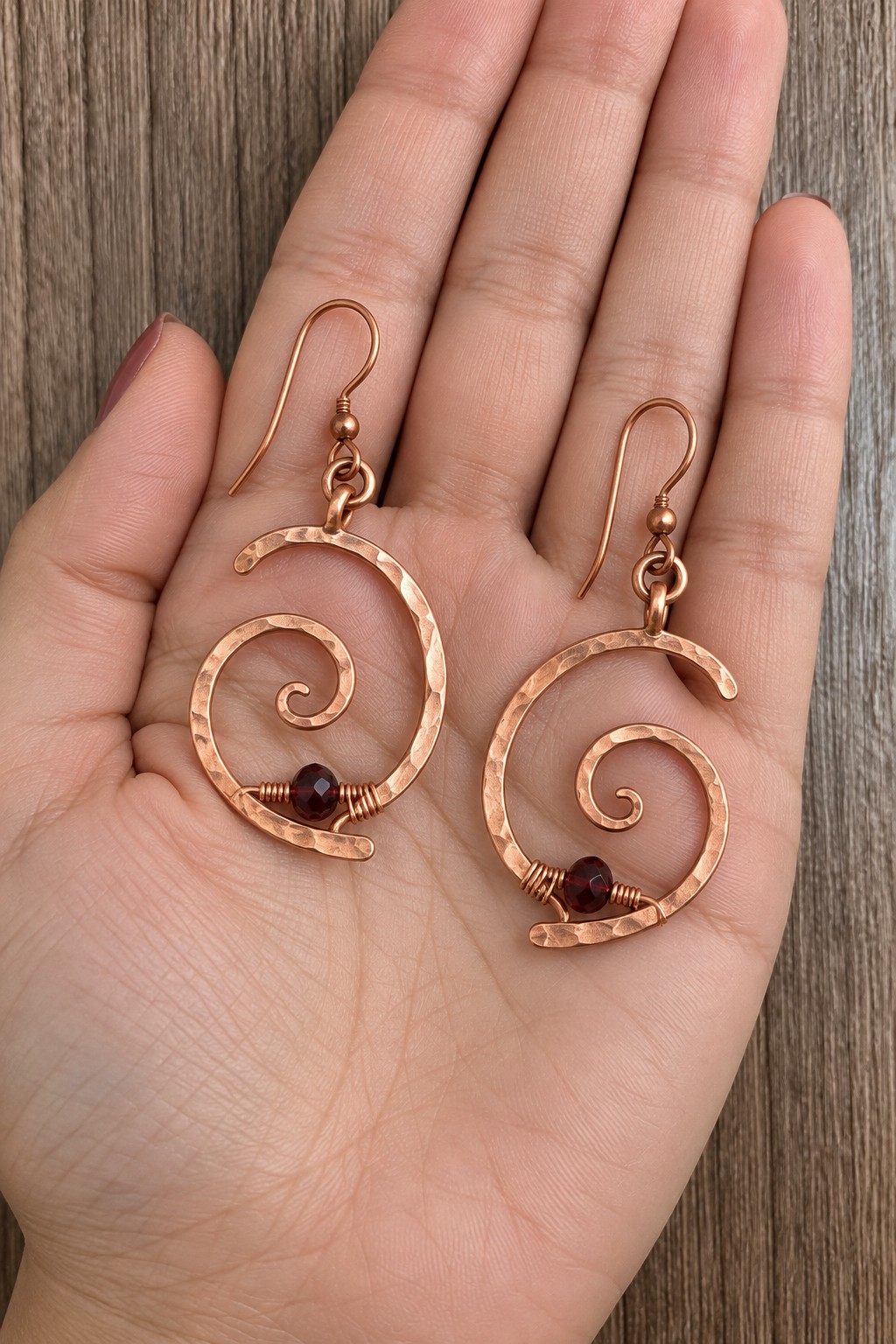 Pair of open hammered copper spiral earrings with small dark red beads