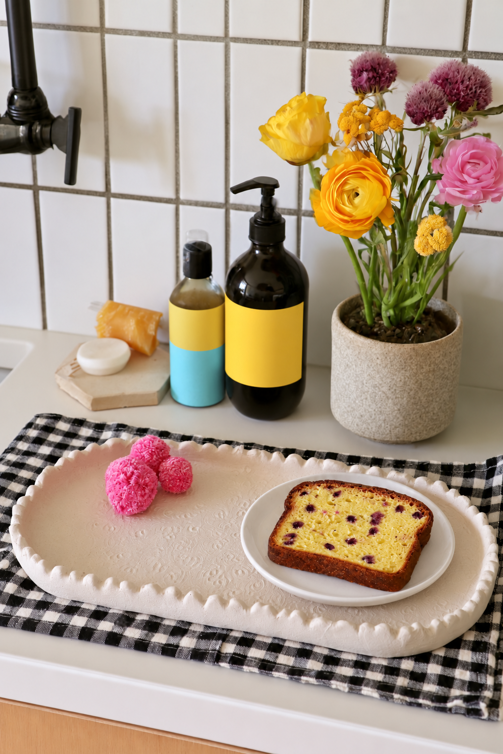 Scalloped clay tray with a cake slice on a separate white plate and pink decorative pompoms