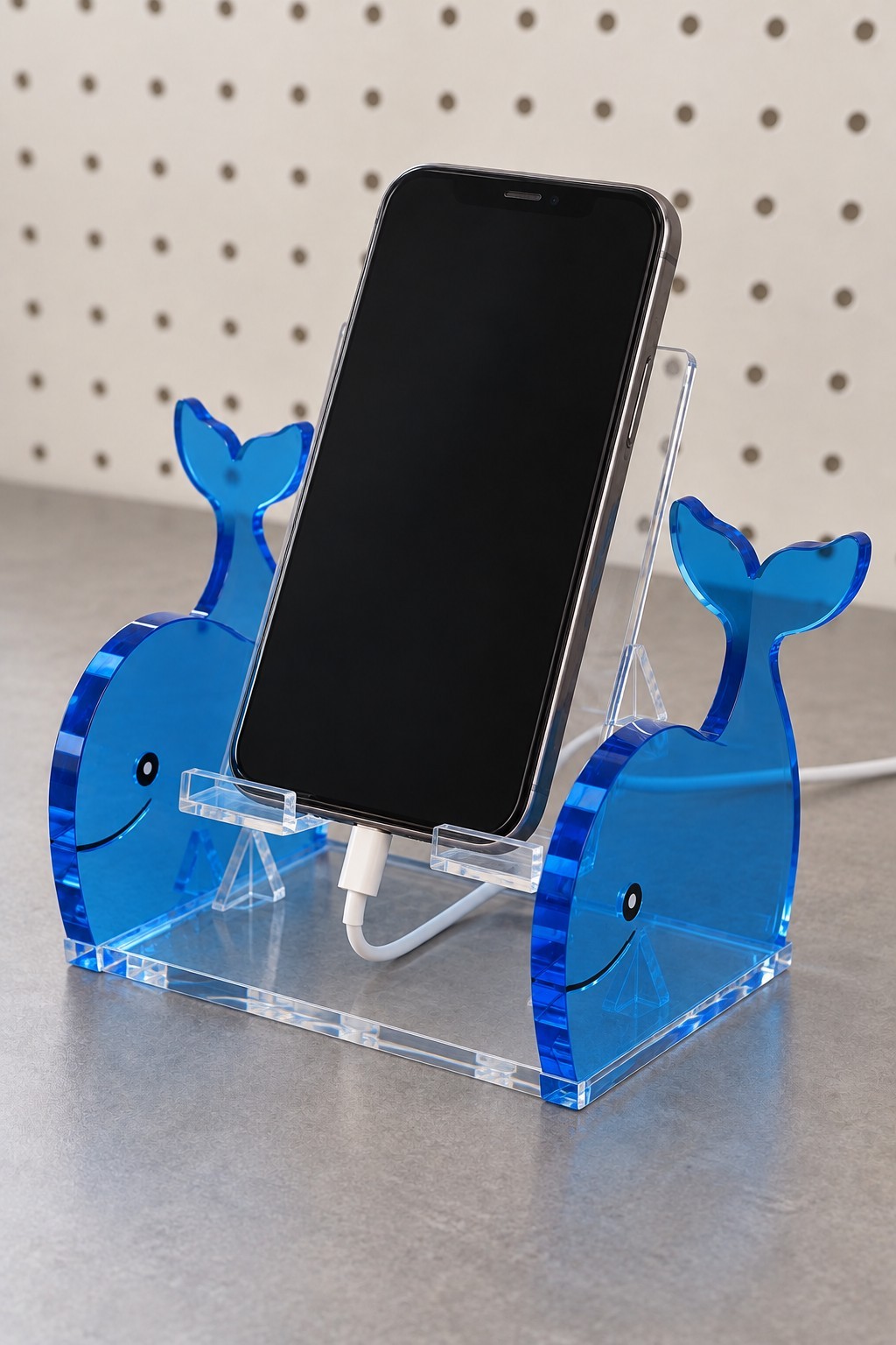 Blue whale acrylic phone stand with a clear angled cradle and charging cable opening