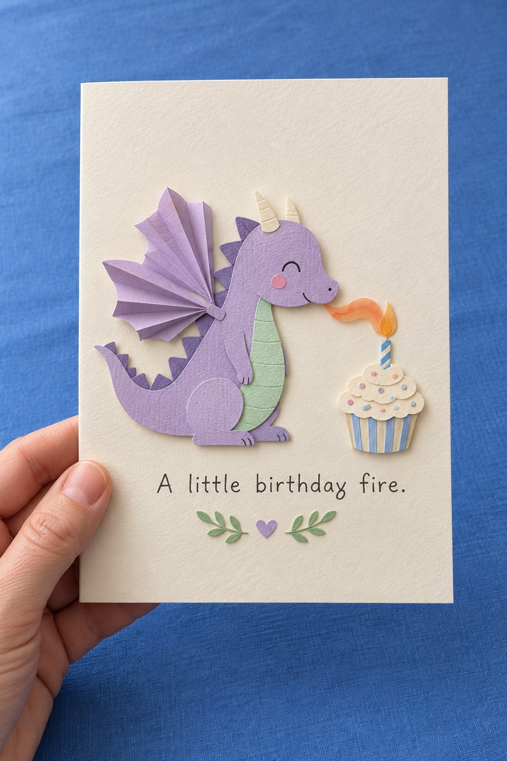 Lavender dragon birthday card with a pleated wing, mint tummy, and a small cupcake