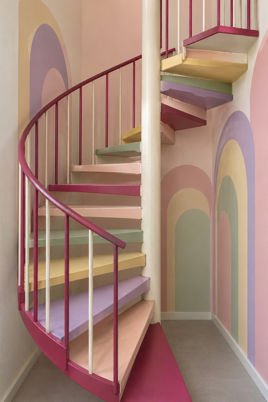Pastel spiral staircase with raspberry railing and overlapping painted arches on the walls