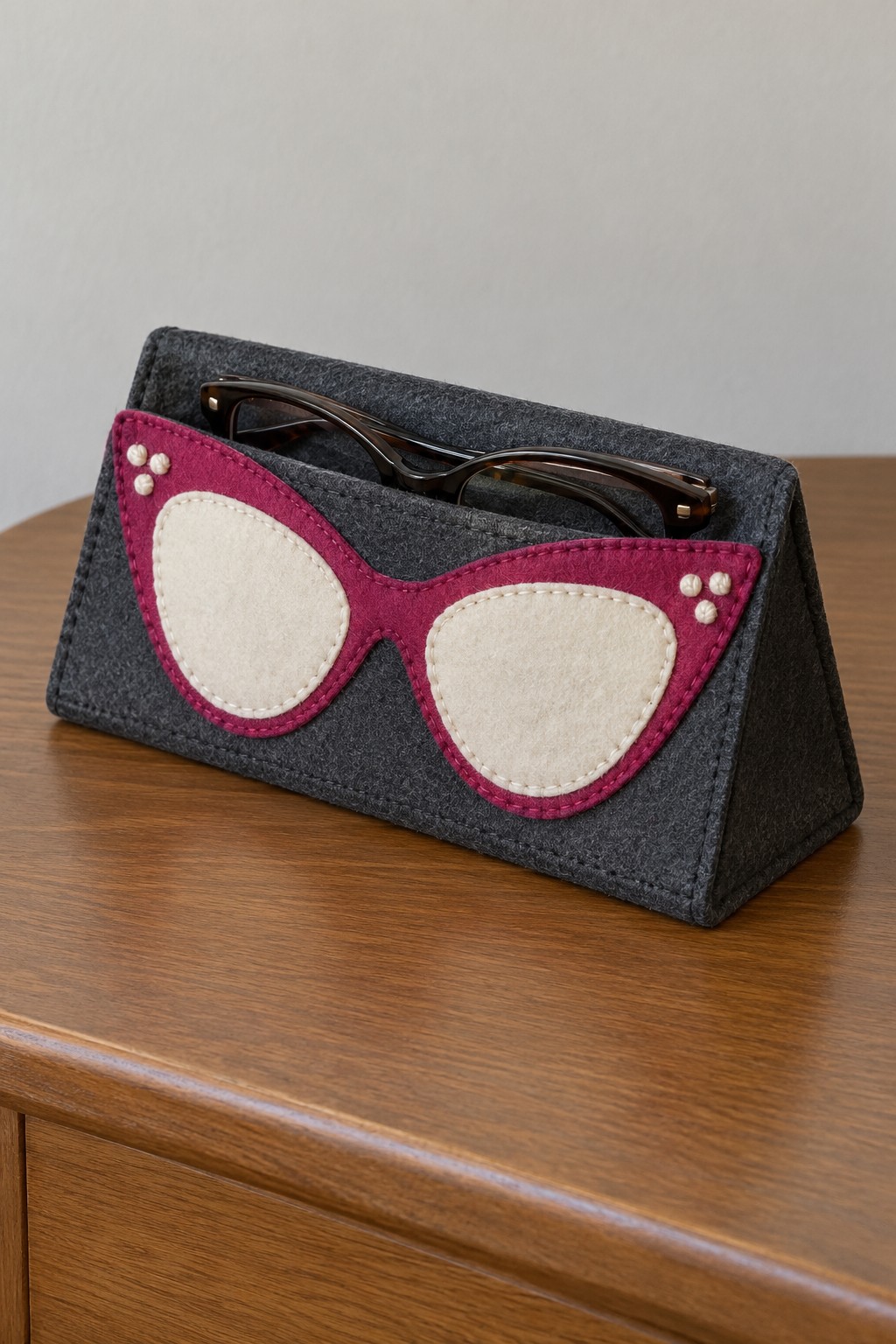 Charcoal triangular eyeglass stand decorated with pink and cream cat eye spectacles