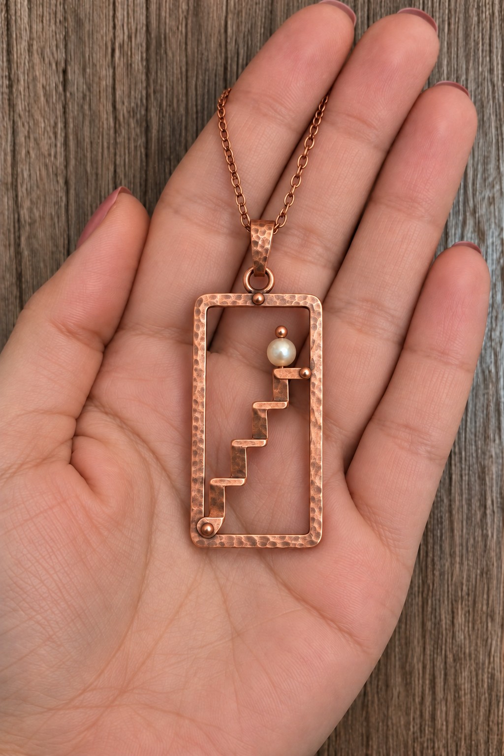 Open rectangular copper pendant with a tiny staircase leading to one pale bead