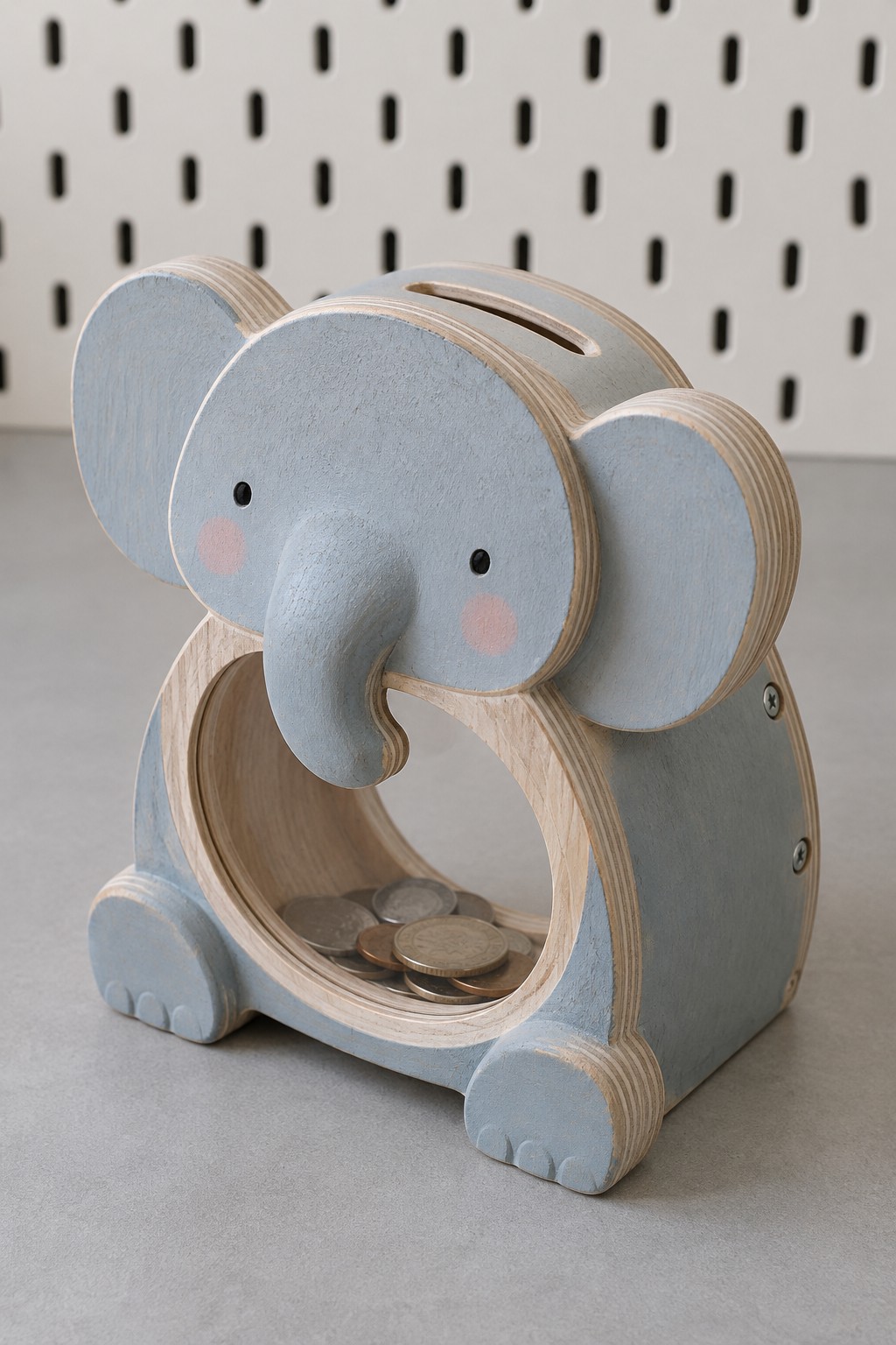 Pale blue wooden elephant coin bank with broad ears, a curved trunk and a clear round tummy