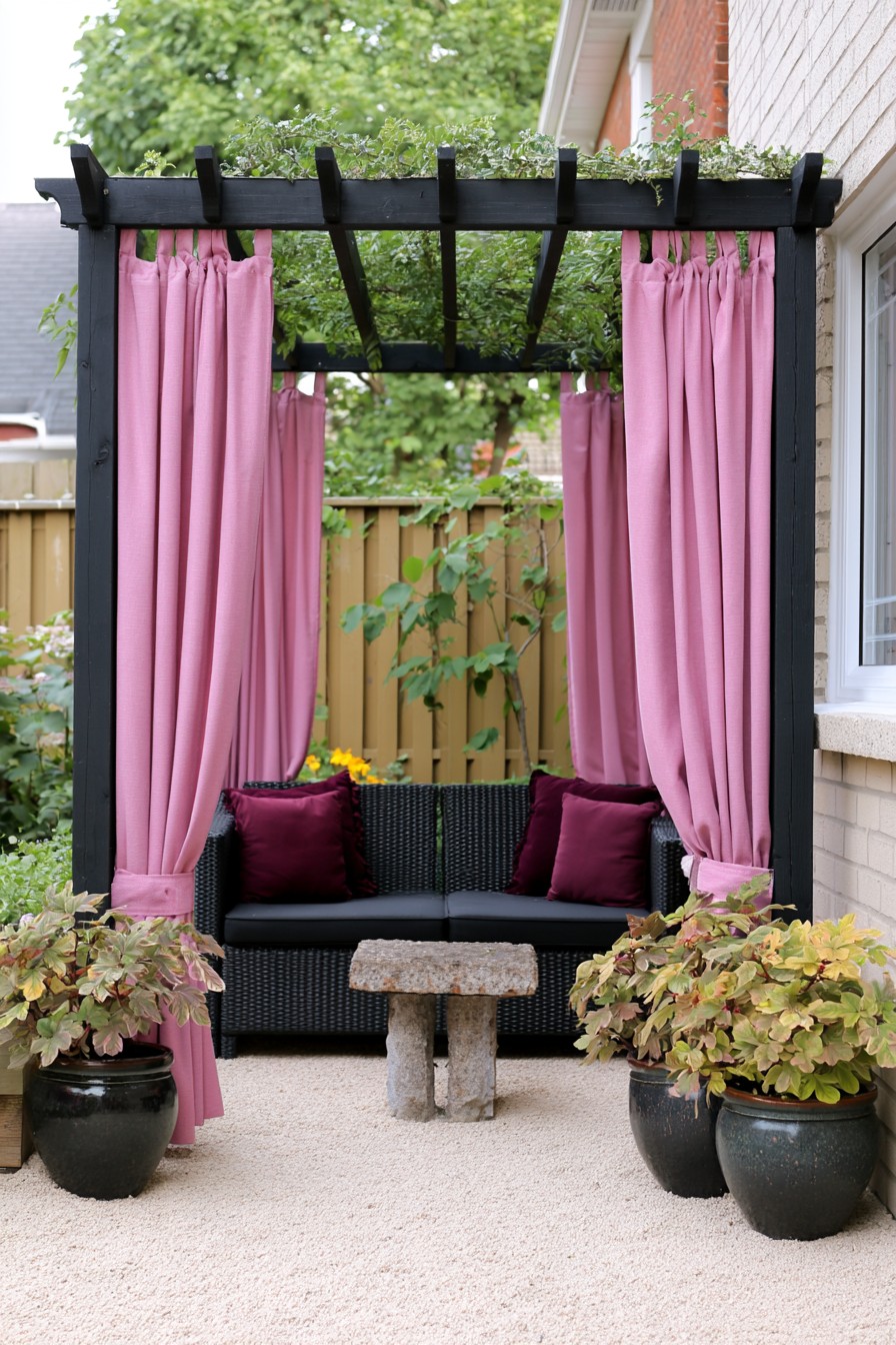 Black pergola with pink curtains, plum cushions, and a compact garden sofa