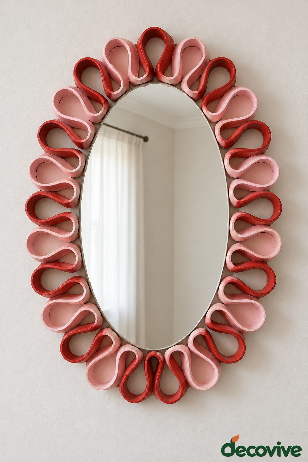 Oval mirror surrounded by alternating blush pink and red cardboard loops