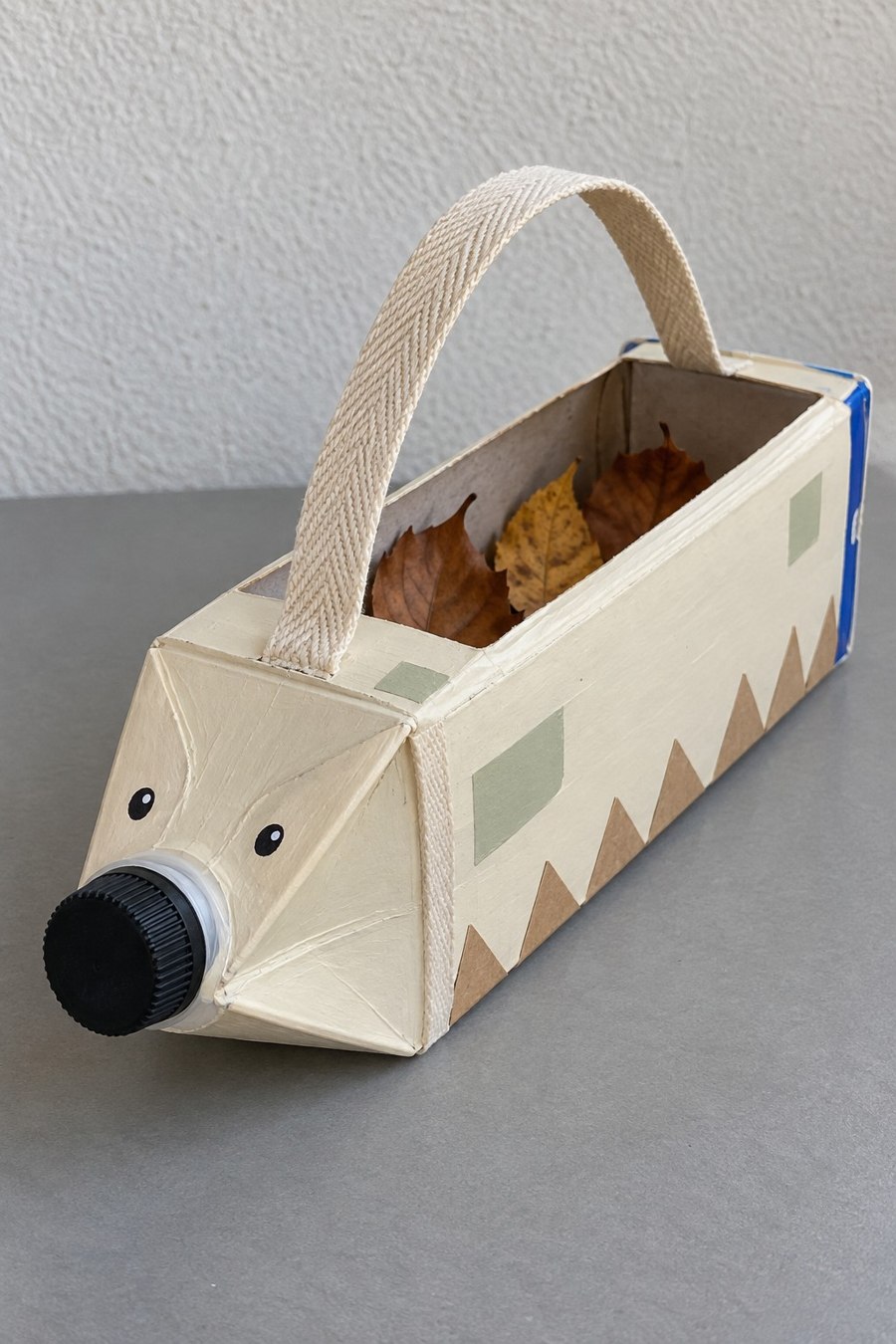 Long hedgehog shaped carton caddy with a black cap nose and fabric handle
