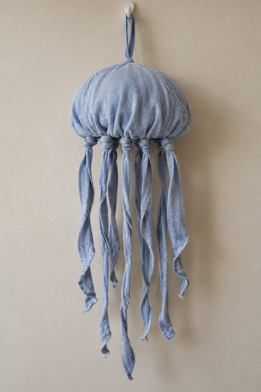 Pale blue fabric jellyfish wall decoration with a gathered dome and long knotted fabric tentacles